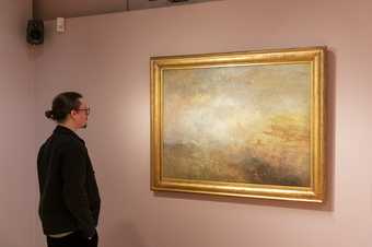 A visitor looking at a painting by JMW Turner