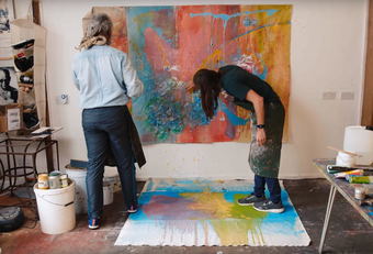Still from the film showing two artists working on a canvas